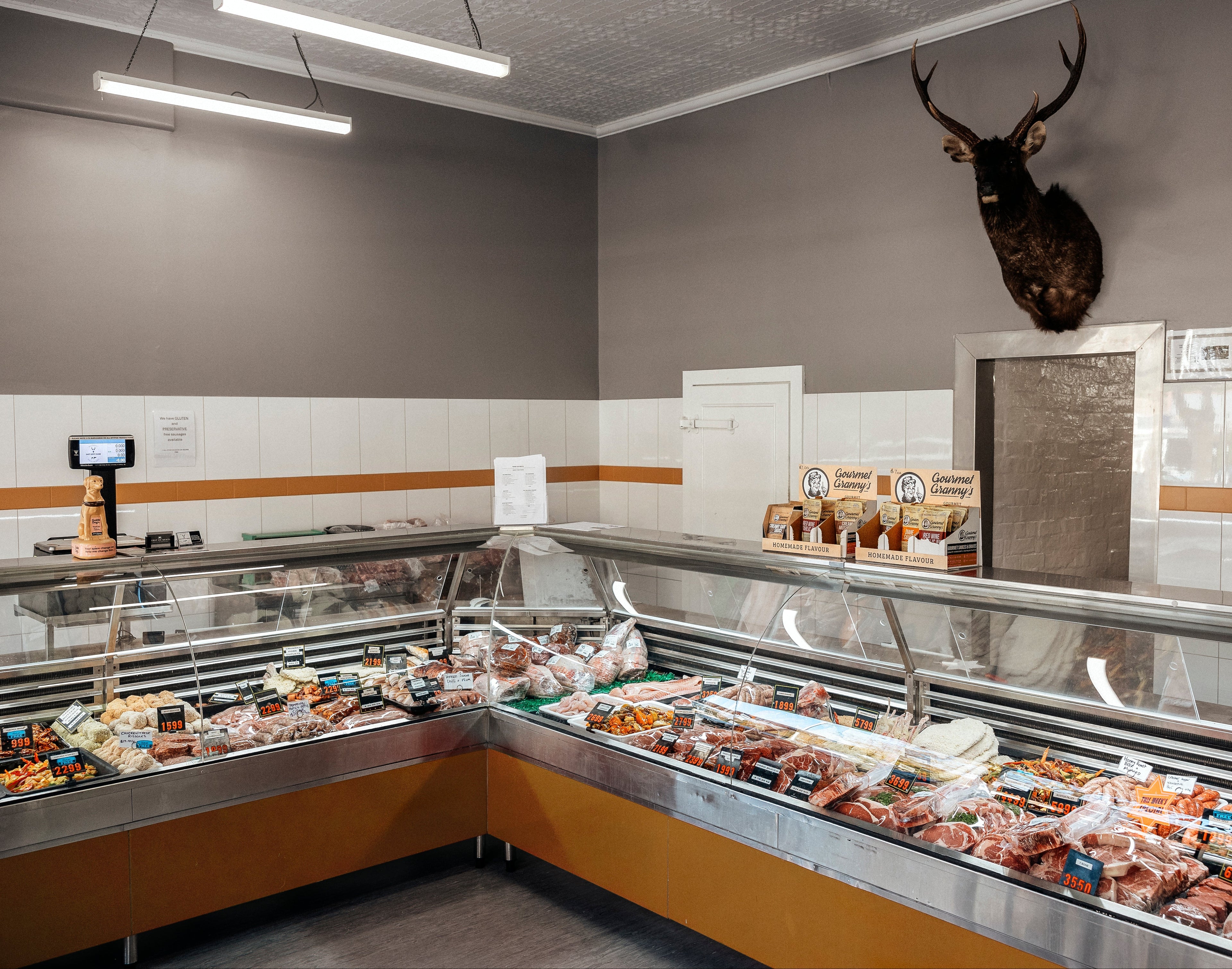 Butcher shop with refrigerated display cases and a deer head mounted on the wall.