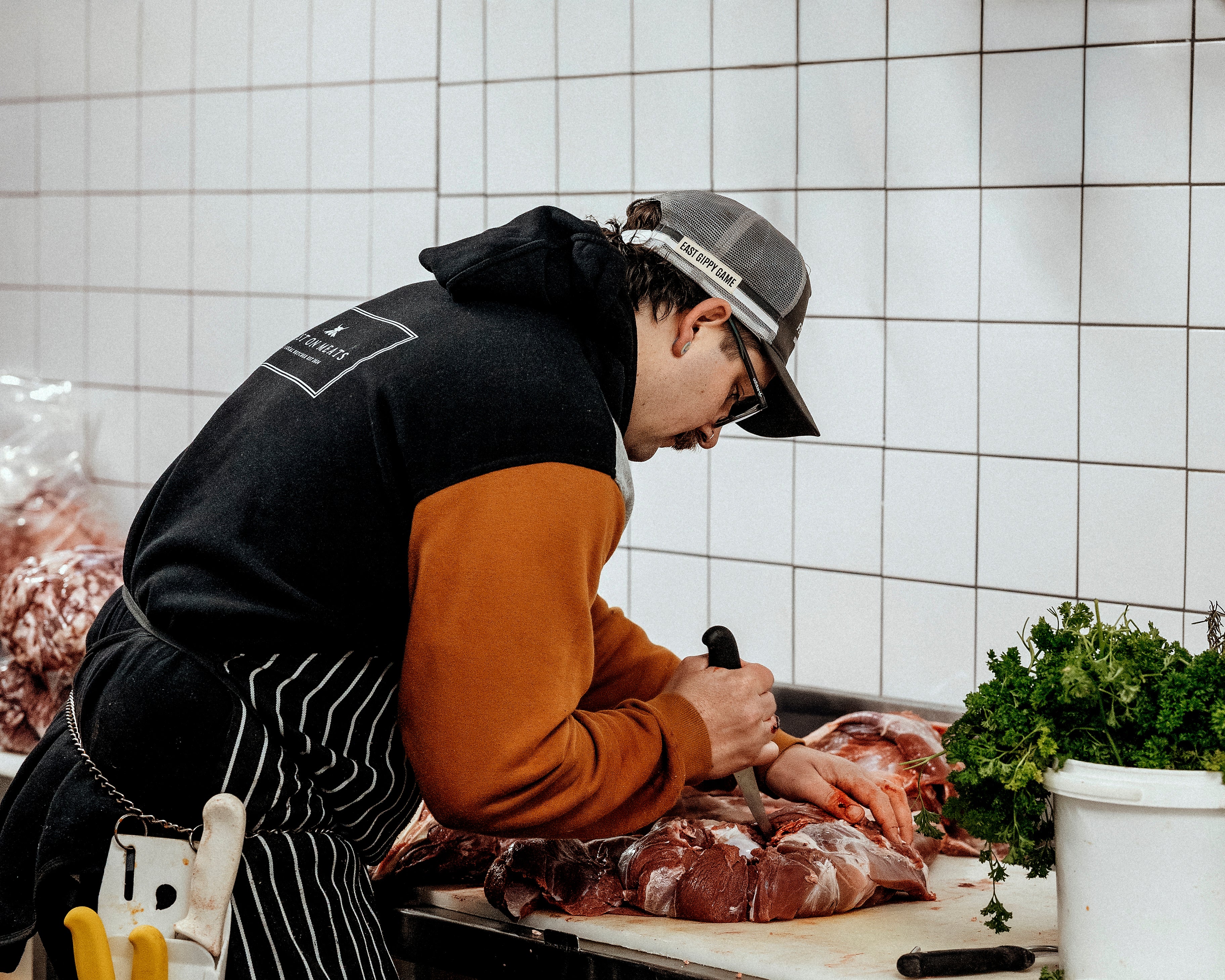 Person butchering an animal in a kitchen with tiled walls.
