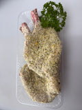 Raw chicken breast with breadcrumb coating on a clear plastic tray with parsley garnish.