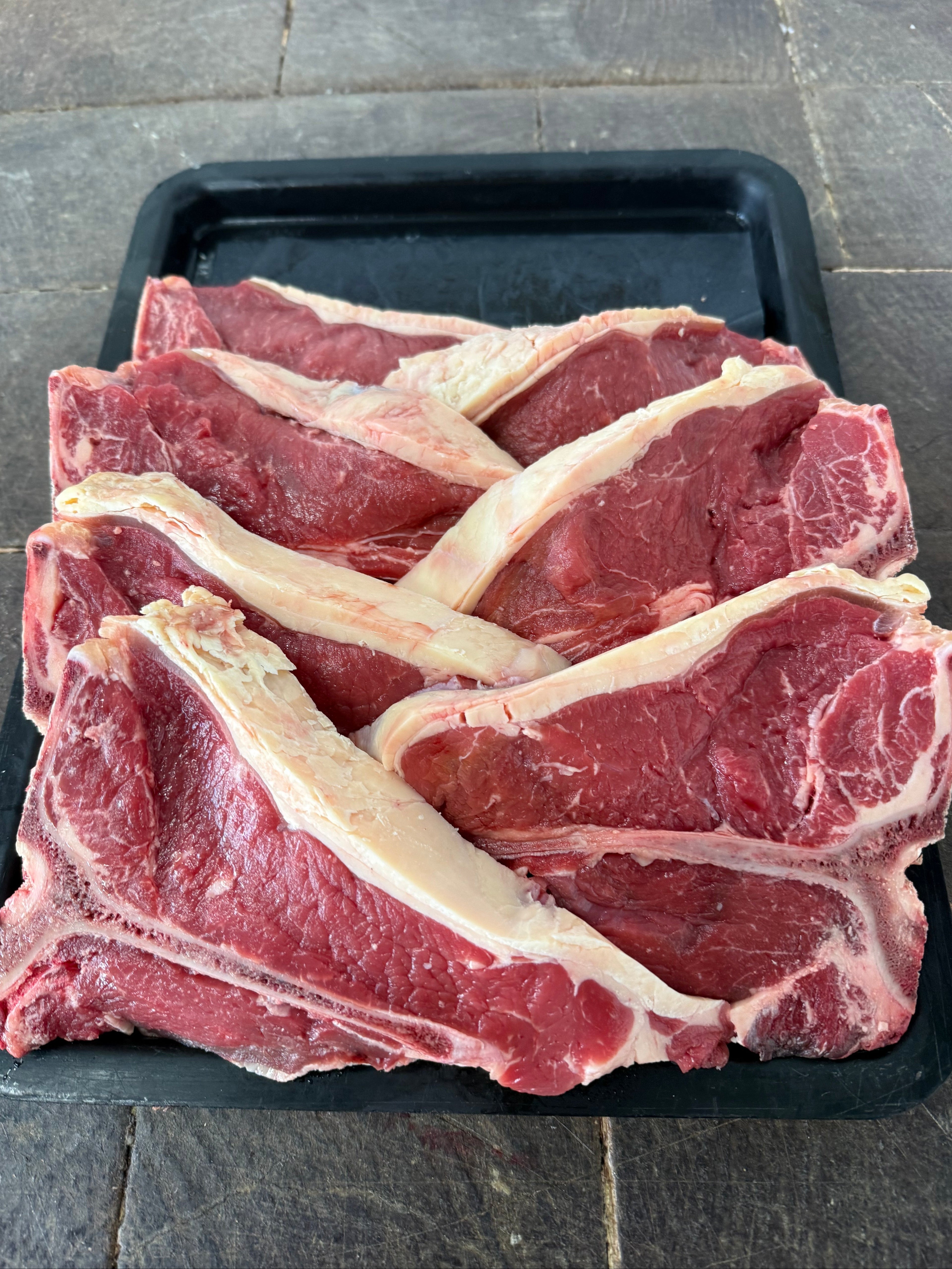 Fresh T-bone steaks on a black tray, hand-cut at Fehst on Meats Maffra