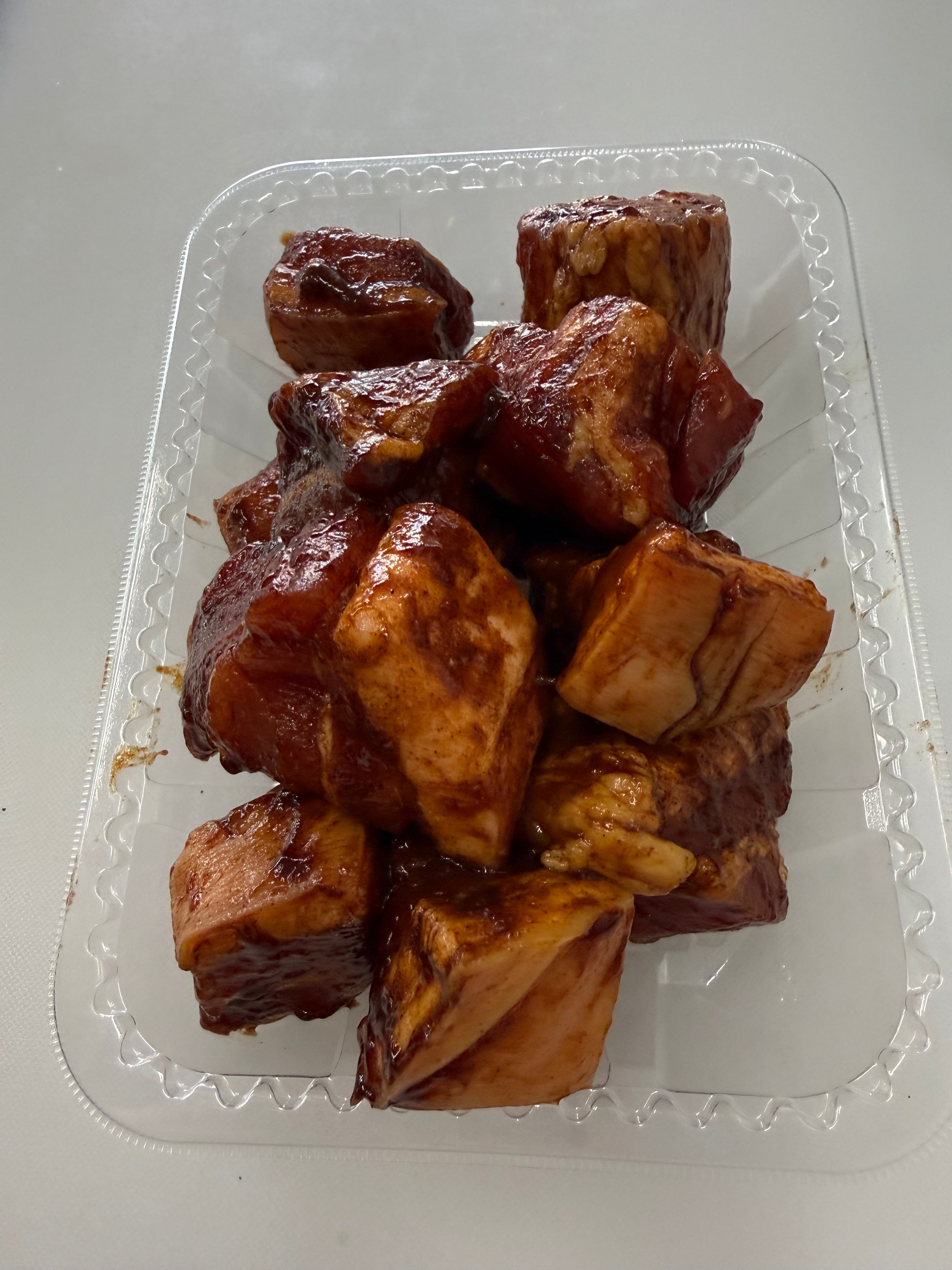 Braised beef bones in a clear plastic container on a white background