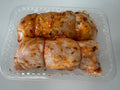 Two rolled-up chicken breasts in a clear plastic container on a white background