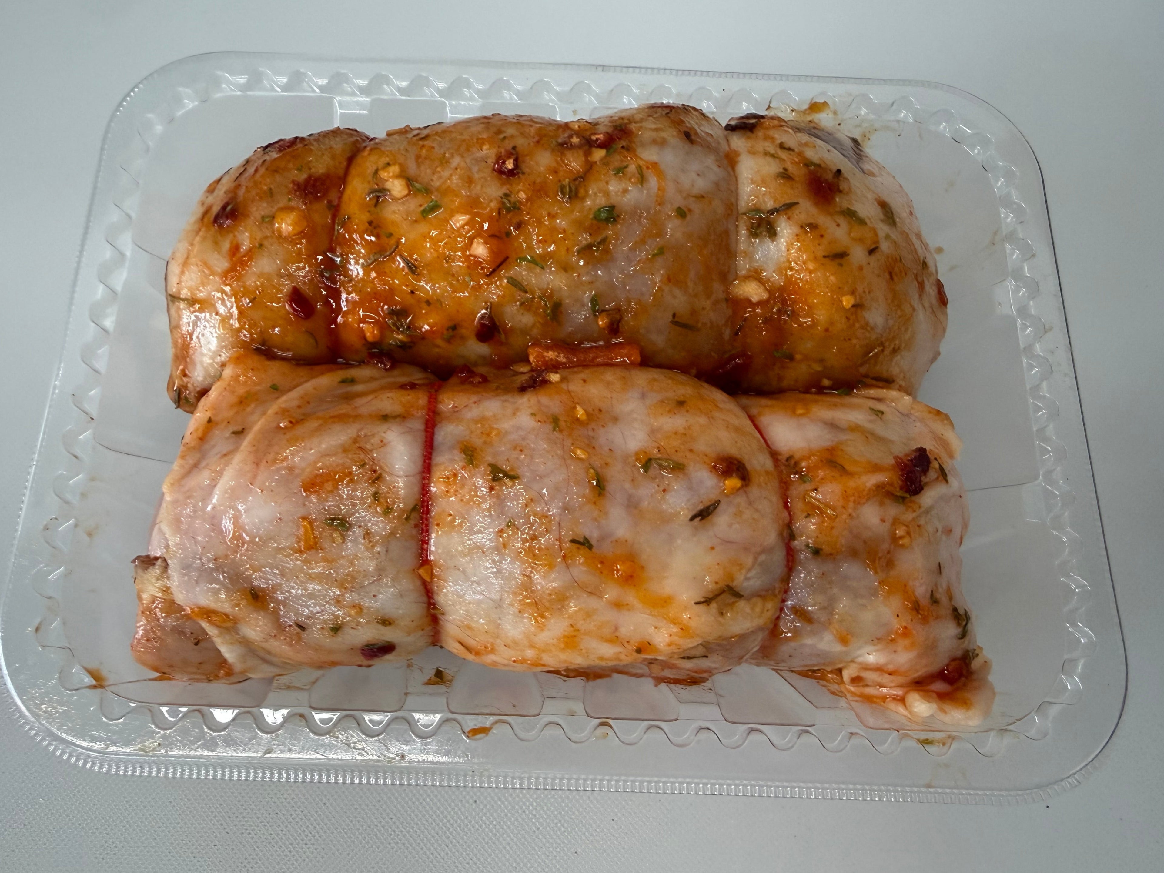 Two rolled-up chicken breasts in a clear plastic container on a white background